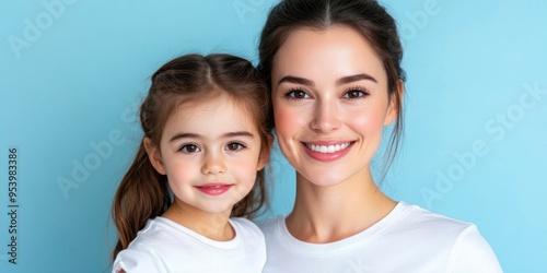 smiling mom and daughter wearing white t shirt and looking at camera against blue background