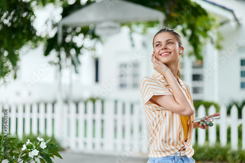 Young woman smiling outdoors, wearing stylish clothing, surrounded by greenery, in a bright atmosphere Feel good and carefree vibes enhance the joyful experience of life