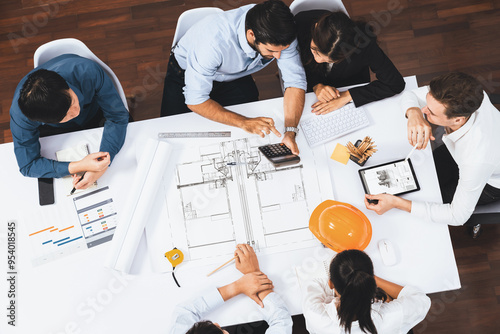 Top view banner of diverse group of civil engineer and client working together on architectural project, reviewing construction plan and building blueprint at meeting table. Prudent