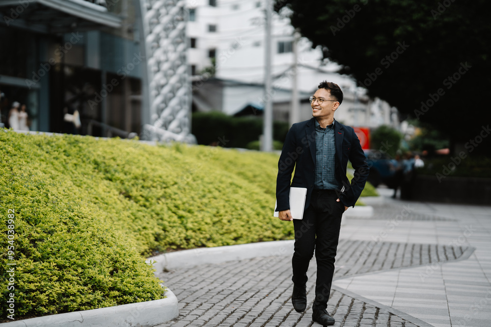 Confident Stride: A young professional, dressed in a sleek suit, confidently walks through a modern cityscape, showcasing a sense of purpose and determination. The man carries a laptop, suggesting a Confident Stride: A young professional, dressed in a sleek suit, confidently walks through a modern cityscape, showcasing a sense of purpose and determination. The man carries a laptop, suggesting a