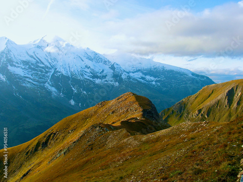 Mountainous landscape with verdant mountain slope in front of bare snow-capped mountain peaks in autumn in Austria. photo