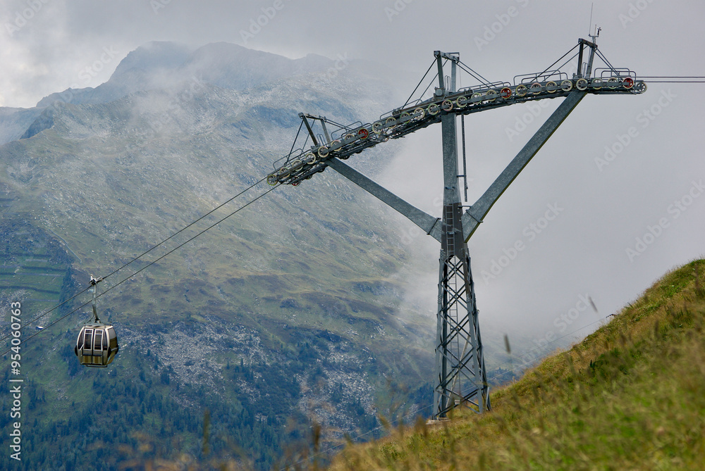 View of an amazing mountain landscape with a gondola lift on a hazy day with gray clouds and fog over the peaks in autumn in Austria. View of an amazing mountain landscape with a gondola lift on a hazy day with gray clouds and fog over the peaks in autumn in Austria.