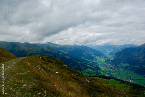 View of an amazing mountain landscape with a village in the valley on a hazy day with gray clouds and fog over the peaks in autumn in Austria. photo