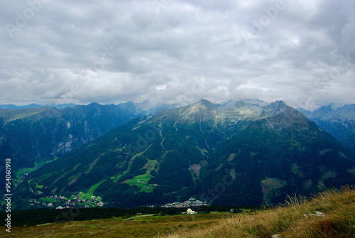 View of an amazing mountain landscape with a village in the valley on a hazy day with gray clouds and fog over the peaks in autumn in Austria.