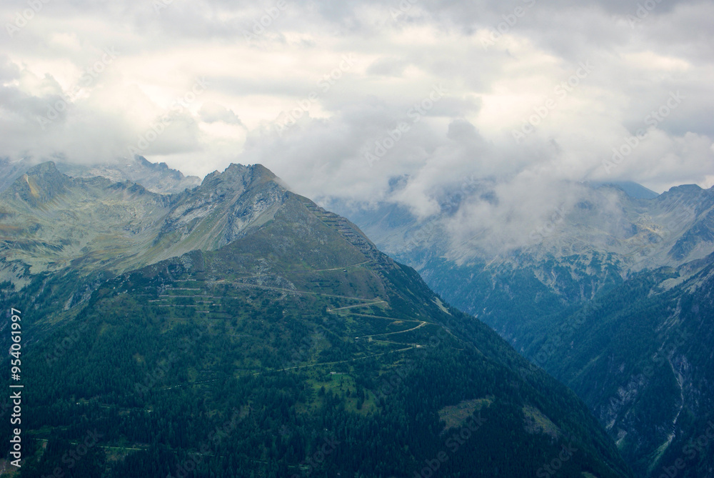 View of an amazing mountain landscape on a hazy day with gray clouds and fog over the peaks in autumn in Austria. View of an amazing mountain landscape on a hazy day with gray clouds and fog over the peaks in autumn in Austria.