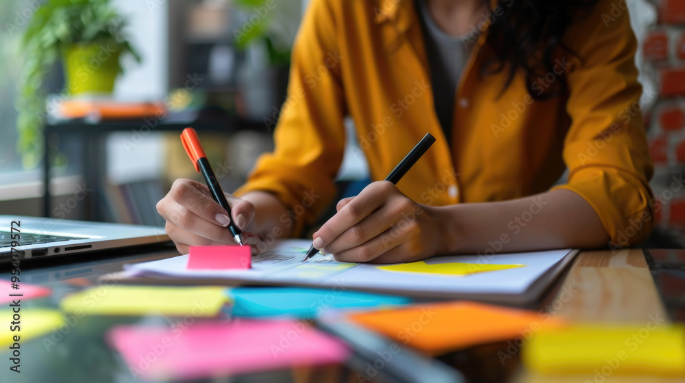 Engagement in a creative task with colorful sticky notes, pens, and a laptop at a bright, modern workspace Engagement in a creative task with colorful sticky notes, pens, and a laptop at a bright, modern workspace