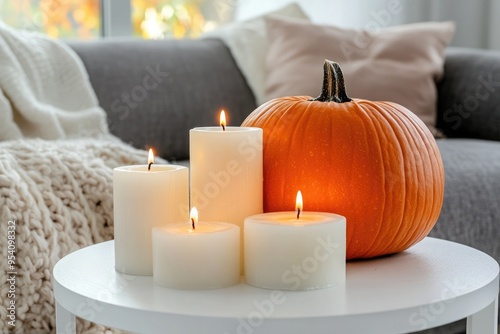 Autumn home decor featuring a pumpkin and lit candles on a table with cozy neutral tones indoors