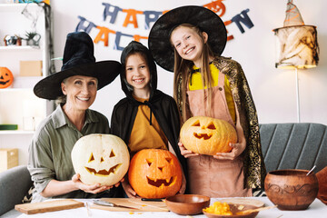 Happy family wearing witches hats posing with pumpkins for halloween celebration