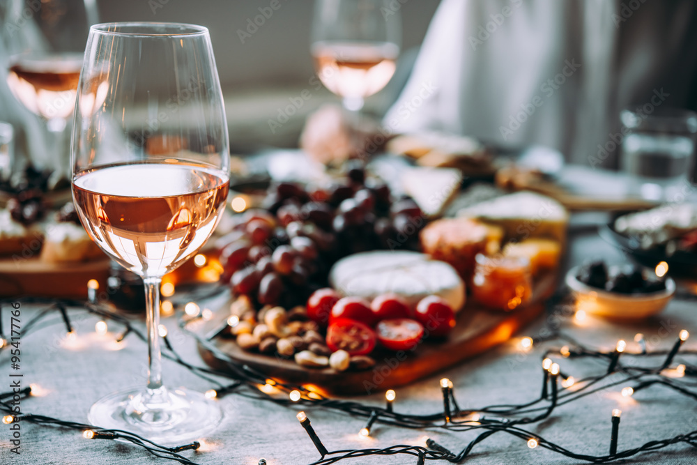 Wooden board with different kinds of cheese and glass of rose wine. Dinner or aperitivo party concept.
