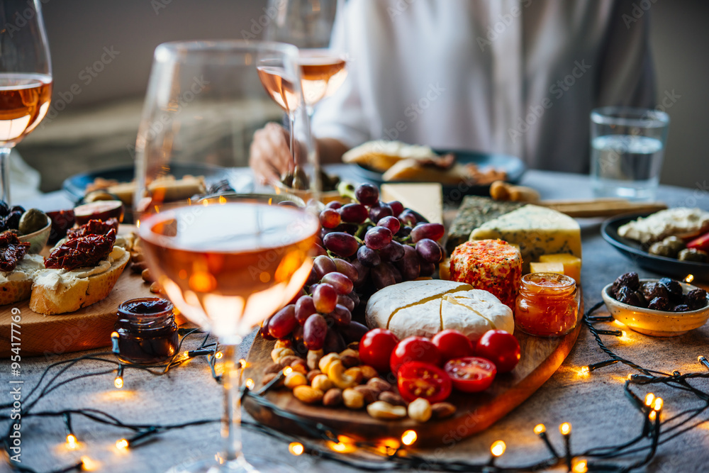 Wooden board with different kinds of cheese and glass of rose wine. Dinner or aperitivo party concept.