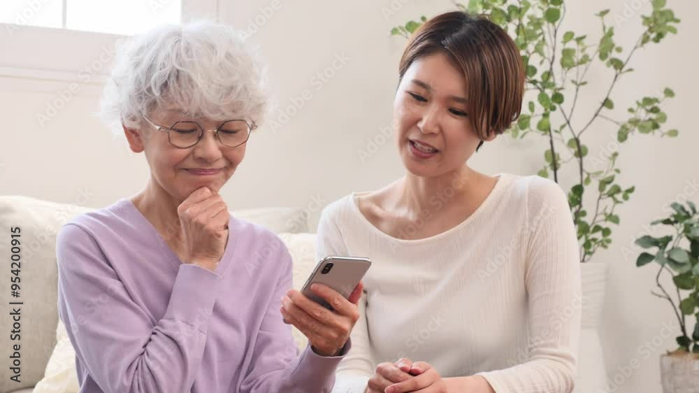 母親にスマートフォンの操作を教える娘 リビングルーム 母親にスマートフォンの操作を教える娘 リビングルーム