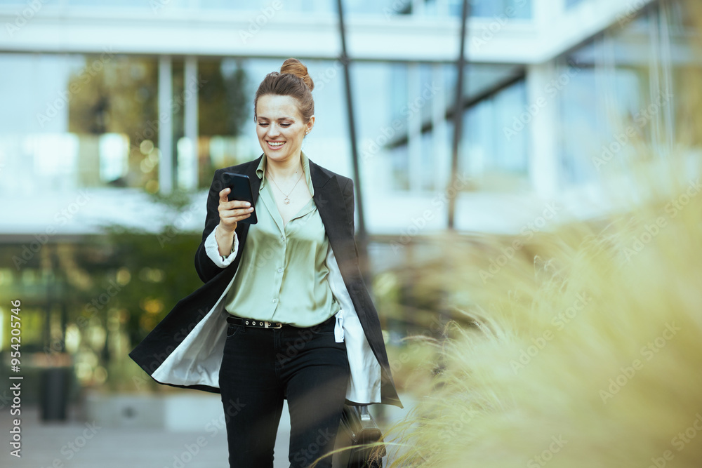 Fototapeta premium woman employee near business center using phone and walking