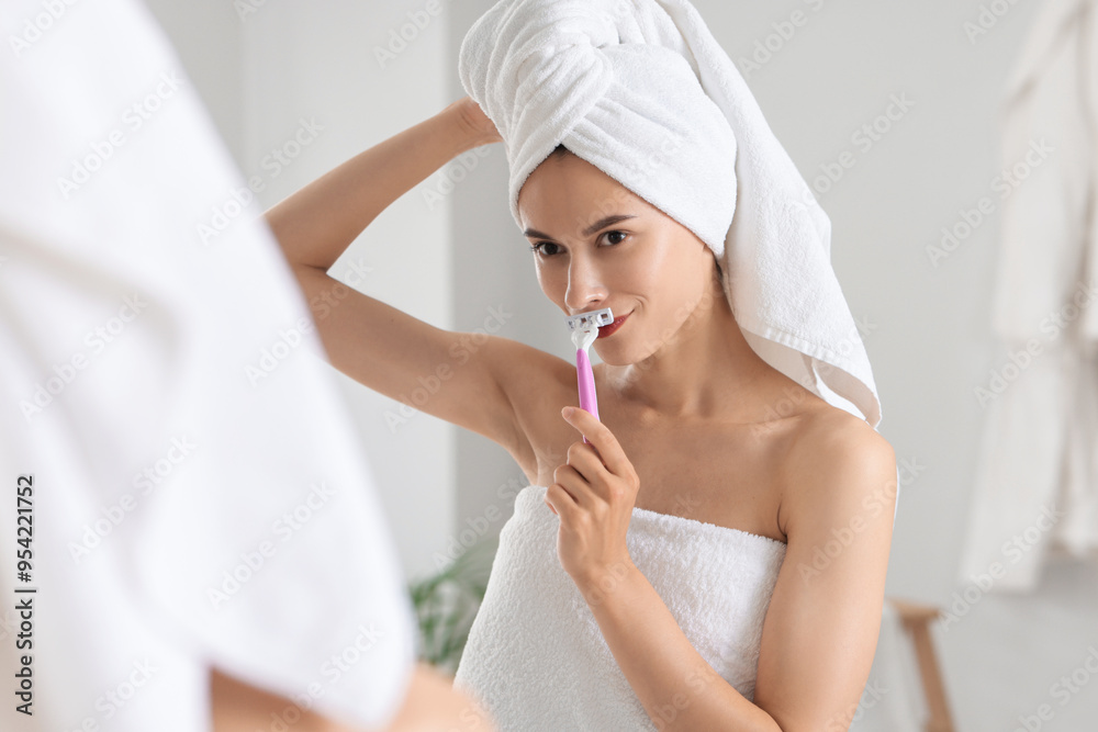 Beautiful woman shaving face near mirror indoors Beautiful woman shaving face near mirror indoors