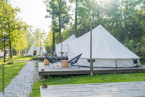 Glamping tents in a serene forest setting with wooden decks and outdoor seating