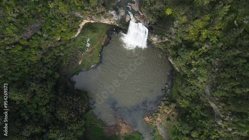 A drone shot of a waterfall in Auckland, New Zealand called Hunua Falls. The waterfall is surrounded by forest. The shot is taken from directly above looking down from above