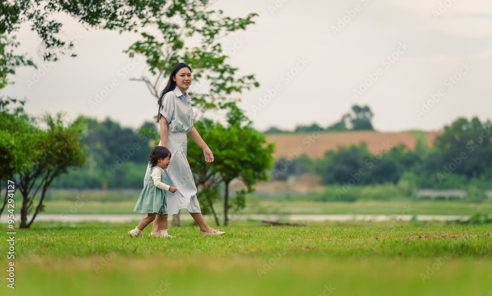Fototapeta premium mother walking with her crying toddler baby girl on grass field in park