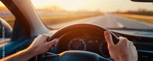 Close-up of hands on the steering wheel, driving down a highway bathed in warm sunset light photo