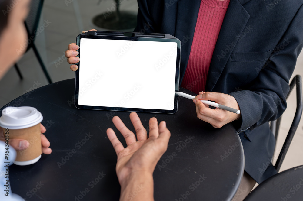 A digital tablet with a white screen mockup on a table during the meeting with two businesspeople. A digital tablet with a white screen mockup on a table during the meeting with two businesspeople.