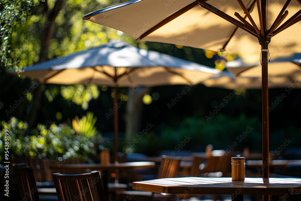 Fototapeta premium Cafe umbrellas, tables, and chairs bathed in sunlight