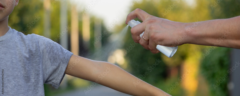 Obraz premium woman applies insect repellent to her son's hand in the park, close-up. Prevention of bites