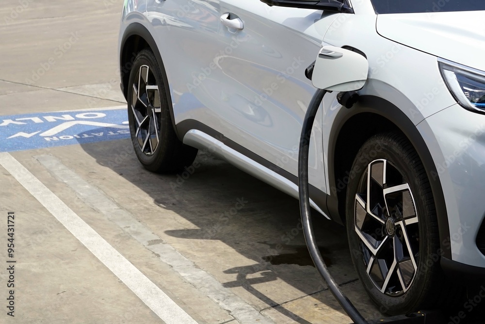 A electric car was charging in the electric car charging station in the carpark in the gas station. A electric car was charging in the electric car charging station in the carpark in the gas station.