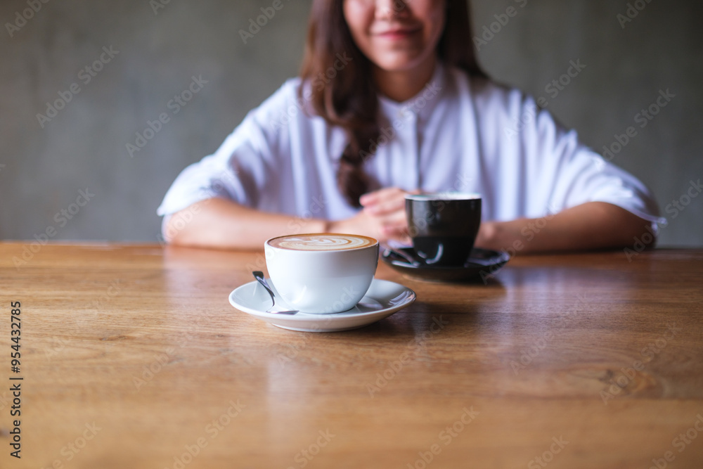 Closeup image of a young woman with two coffee cups on wooden table Closeup image of a young woman with two coffee cups on wooden table