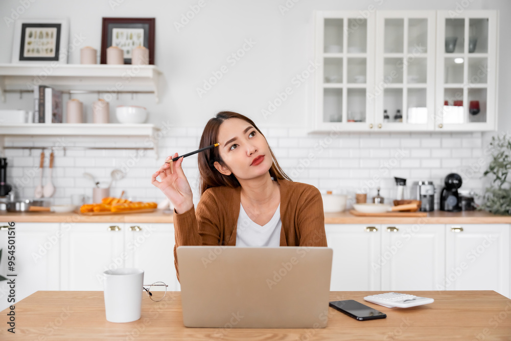 Asian young woman seriously working on computer laptop in house. She thinking find solution problem of work Asian young woman seriously working on computer laptop in house. She thinking find solution problem of work