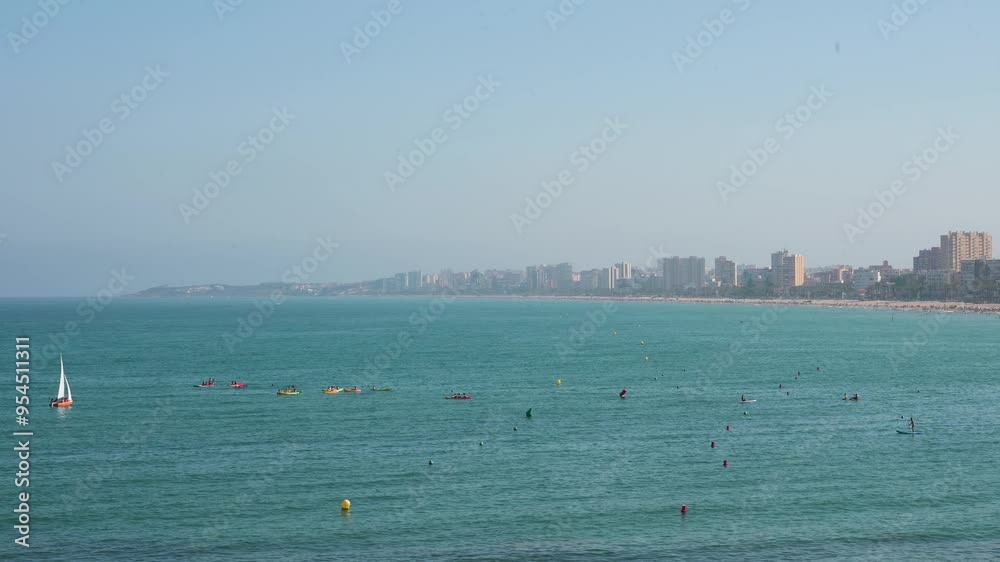 The beautiful Mediterranean scene at El Campello, Costa Blanca, Alicante, featuring a sailboat and people enjoying various water sports. The beautiful Mediterranean scene at El Campello, Costa Blanca, Alicante, featuring a sailboat and people enjoying various water sports.