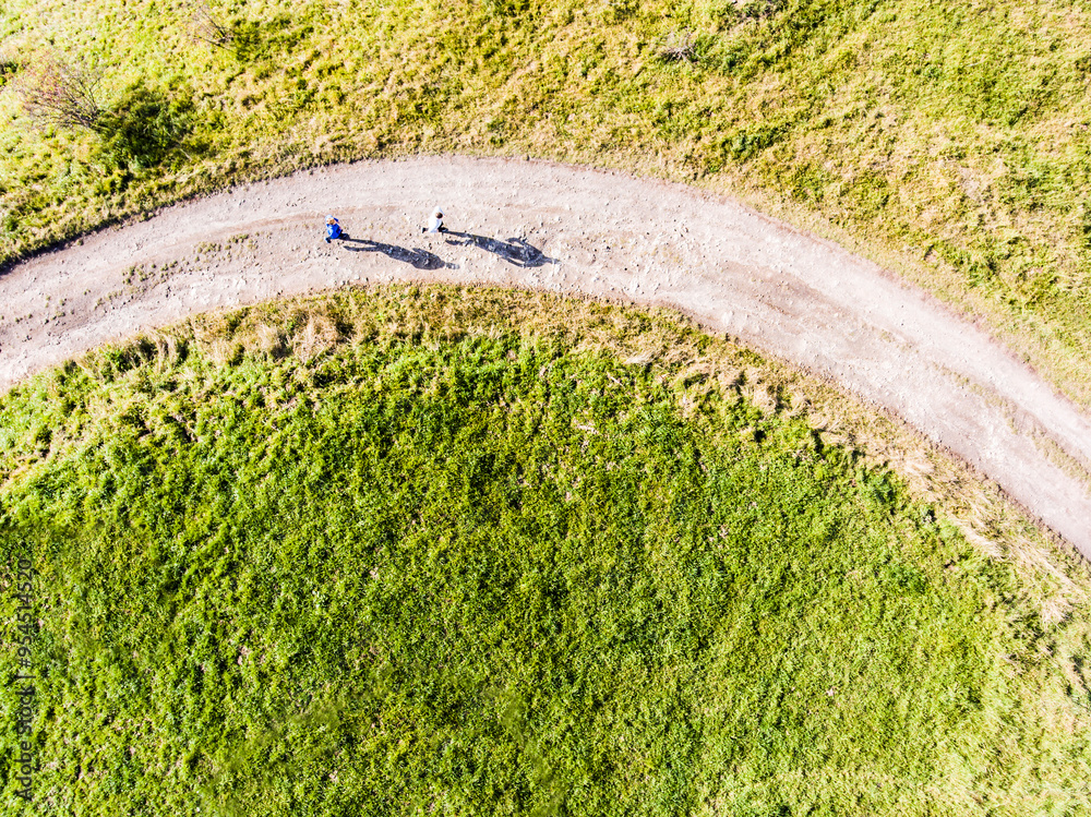 Fototapeta premium Aerial view of two runners jogging on dirt running trail in nature. Morning running training for friends.