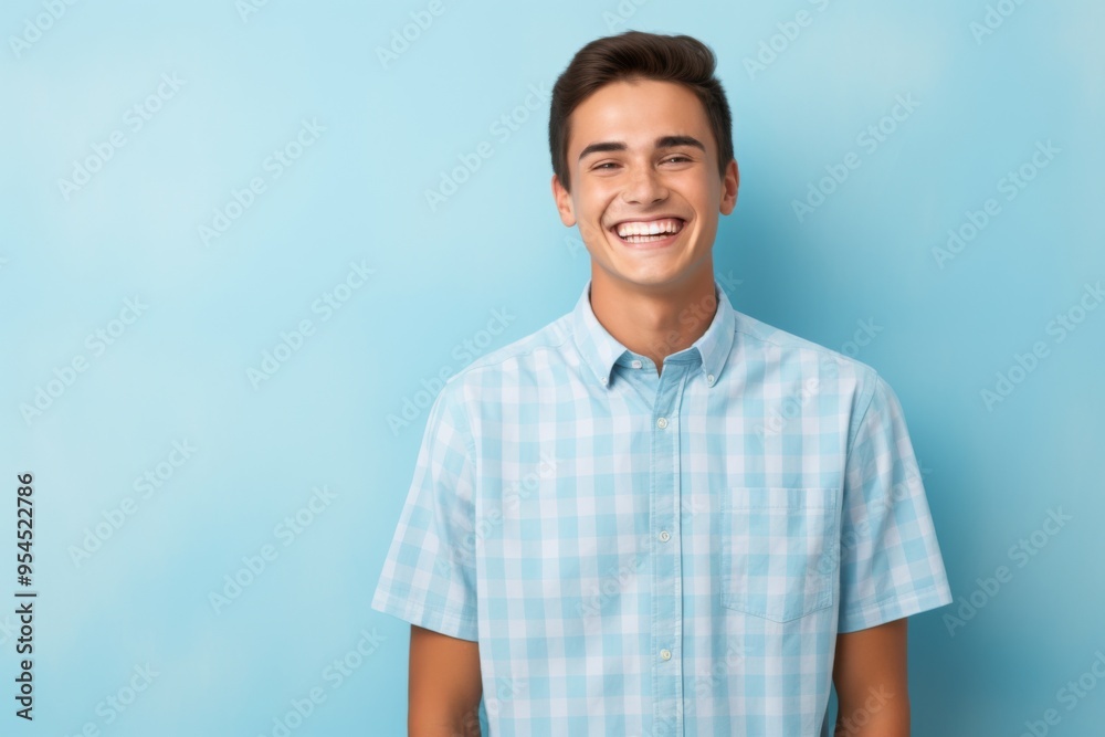 Fototapeta premium A young man is smiling and wearing a blue plaid shirt
