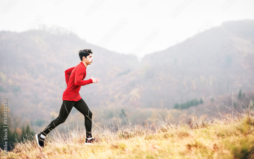 Fototapeta premium Male runner jogging in nature on dirt running trail. Morning running training for young man.