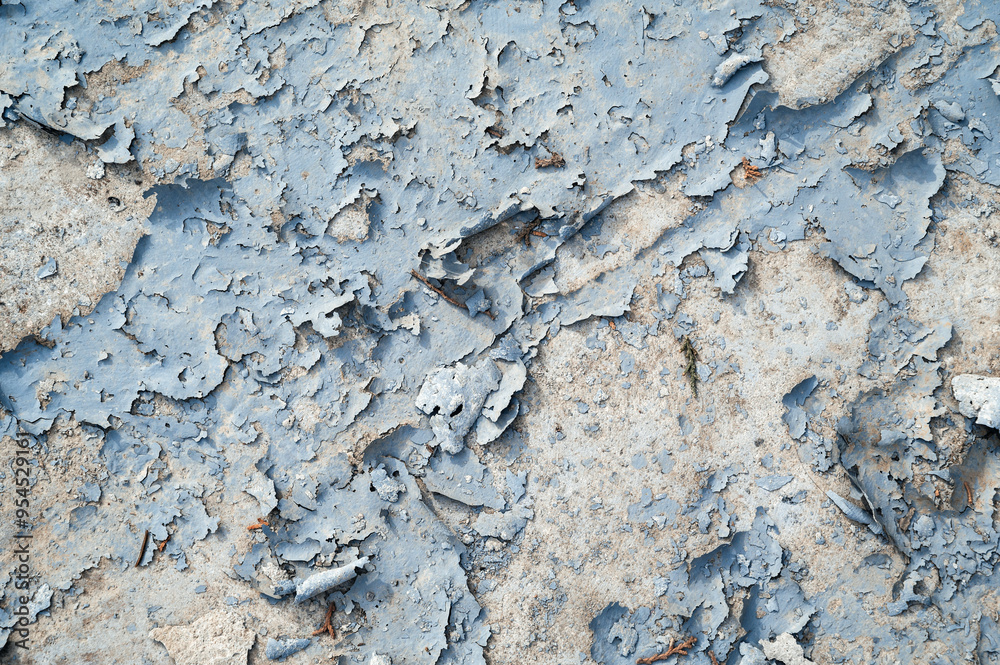 Fototapeta premium a concrete wall with old cracked flaking paint. Weathered rough painted surface with patterns of cracks and peeling.