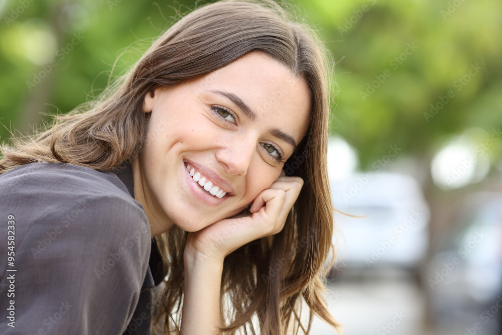 Happy woman with perfect smile and teeth looks at camera in a park Happy woman with perfect smile and teeth looks at camera in a park