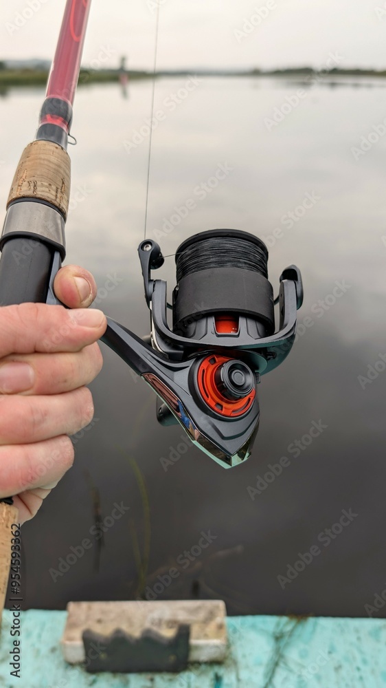 Hand holding fishing rod and reel, fishing at Corrib river at Galway, Ireland, spinning, angling, catch and release, sport and leisure, nature background