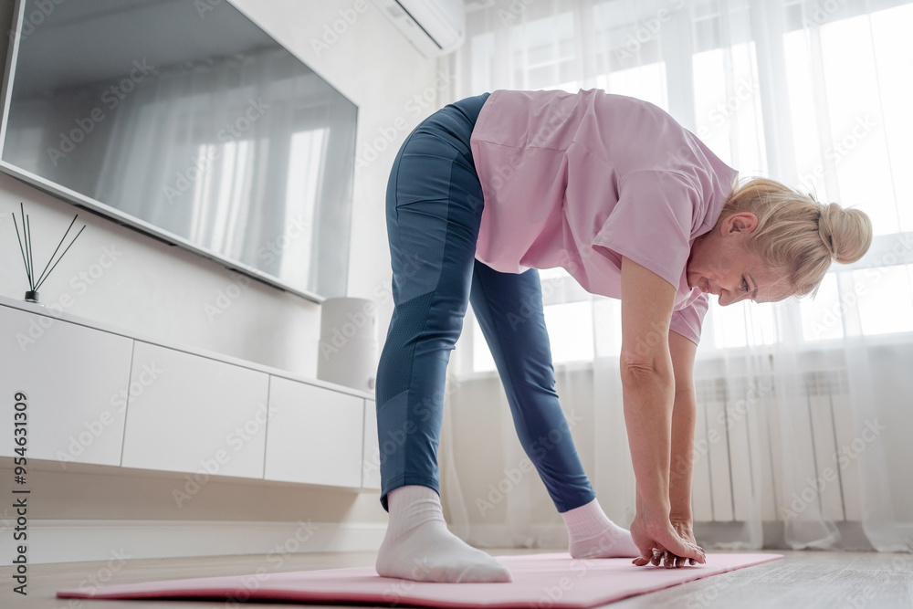 Practicing yoga, a woman is in her cozy living room, surrounded by calm energy and natural light Practicing yoga, a woman is in her cozy living room, surrounded by calm energy and natural light
