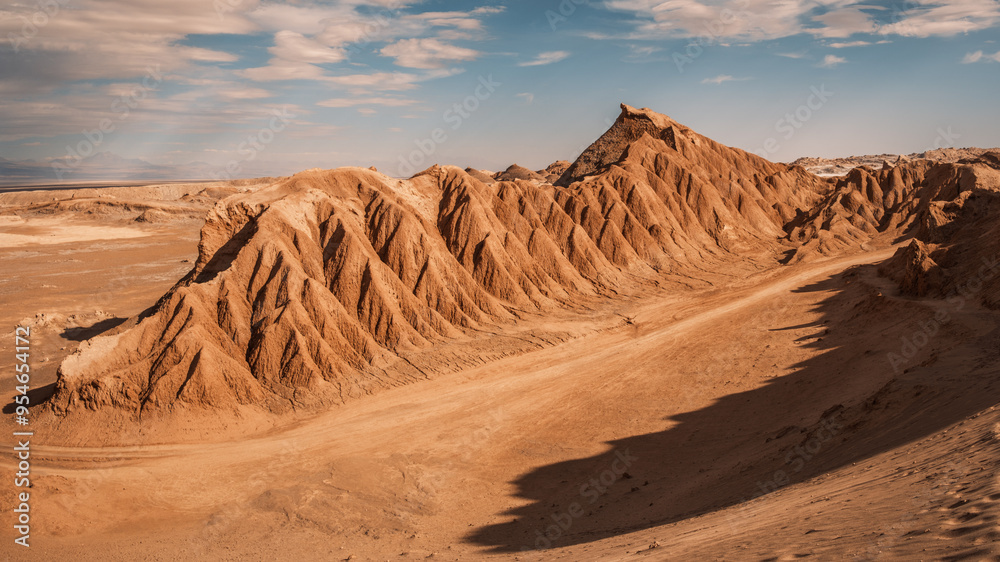 Naklejka premium Vast, sculpted mountains characterize the arid landscape of Cordillera del Sal, showcasing striking geological formations under a clear sky, San Pedro de Atacama, Chile