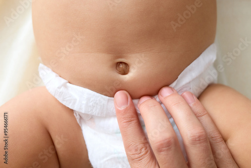 Fotografie Caring unrecognizable woman making loving touch for child navel unknown baby wea