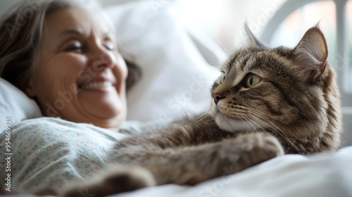 A cat rests beside a smiling woman patient in a hospital bed, highlighting the joy and healing of pet therapy. Copy space.