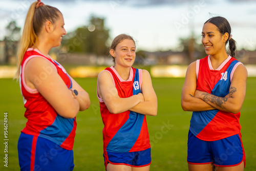 three young women on football field with their arms crossed photo