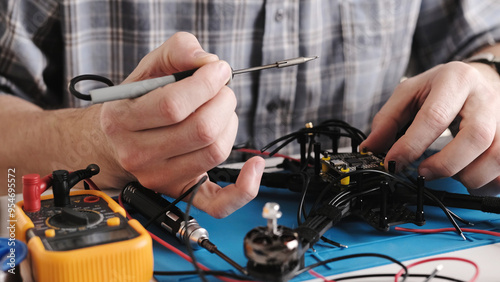 Repair Man Soldering Wires And Microchip Board On FPV Hobby Drone At Service Center photo
