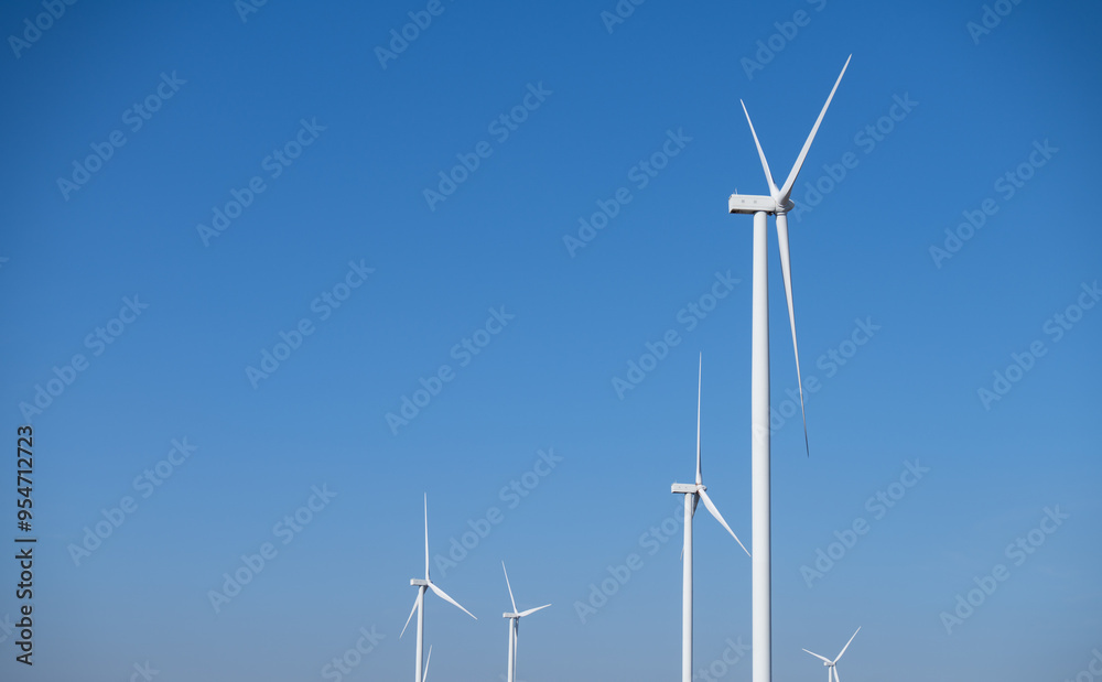 A group of wind turbines against blue sky, Wind energy. Wind power. Sustainable, renewable energy. Wind turbine generate electricity. Sustainable resources. Green technology for energy sustainability. A group of wind turbines against blue sky, Wind energy. Wind power. Sustainable, renewable energy. Wind turbine generate electricity. Sustainable resources. Green technology for energy sustainability.