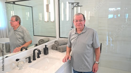 man adjusts his hair and takes care of his vanity in his new marble walled bathroom