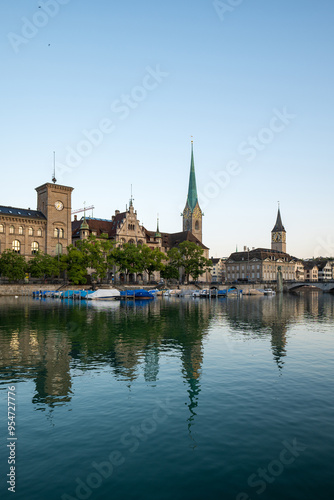 Downtown Zurich city, Switzerland. Riverside view of the Limmat, Fraumunster and Saint Peter church towers. Sunny summer day, boats docked on the pier