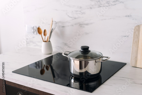 Stainless steel pan with lid at glass ceramic hob on kitchen