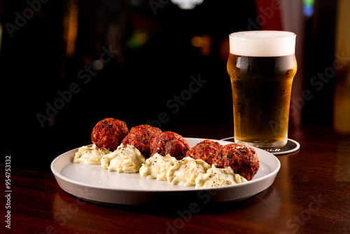 close up of portion of meatloaf with mayonnaise pint of craft beer on wooden table at pub happy hour blurred in the background photo