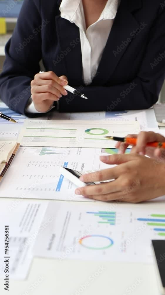 Financial analysts strategizing on charts and data during a meeting. Financial analysts discuss charts and graphs, using calculator to analyze data during a business meeting. Financial analysts strategizing on charts and data during a meeting. Financial analysts discuss charts and graphs, using calculator to analyze data during a business meeting.