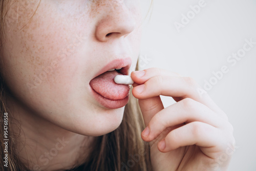 Teenage girl taking a pill, close-up view