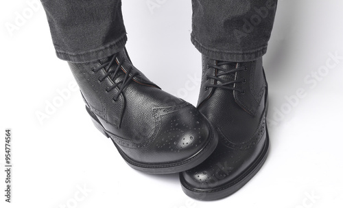 Male legs in black leather brogue boots on a white background