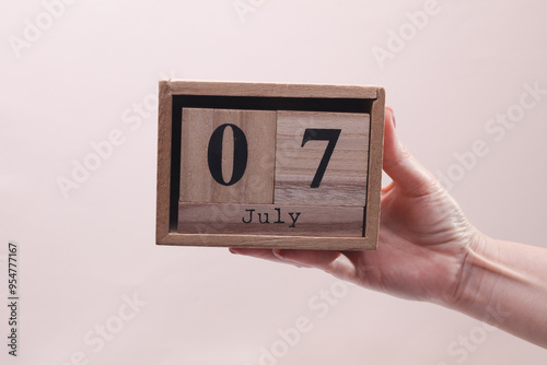 Wallpaper Mural Female Hand holding wooden block calendar with the date July 7 on beige background Torontodigital.ca