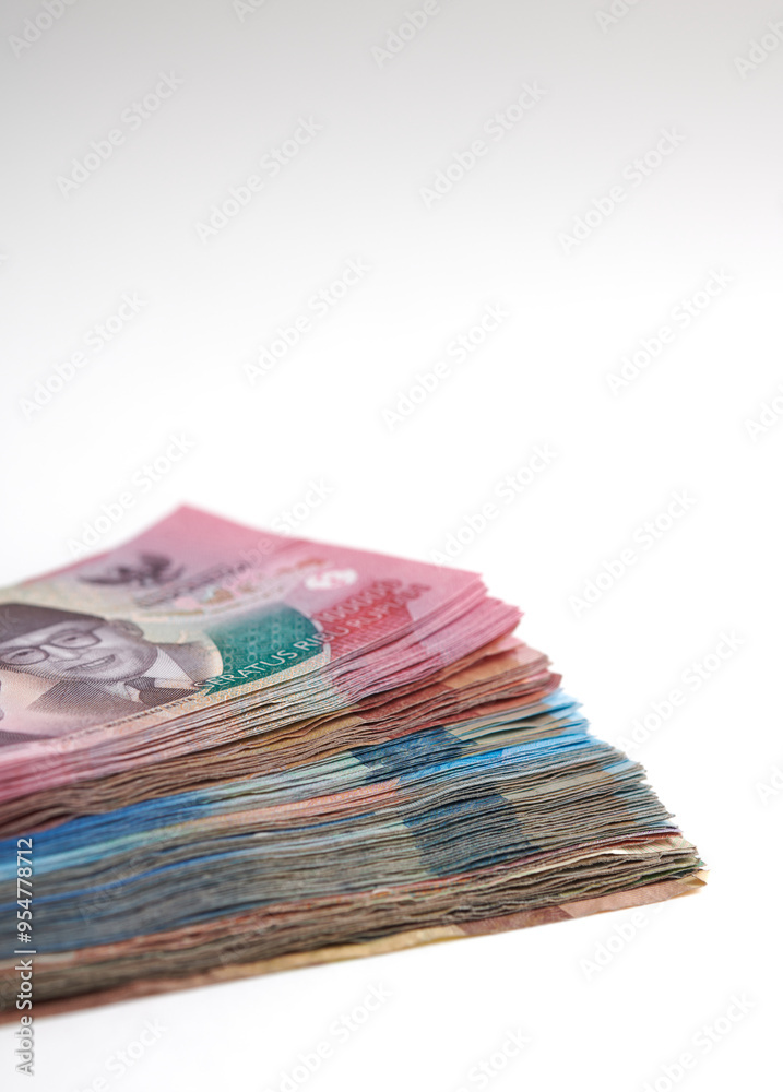 A stack of various Indonesian rupiah banknotes on a white background. Selective focus A stack of various Indonesian rupiah banknotes on a white background. Selective focus